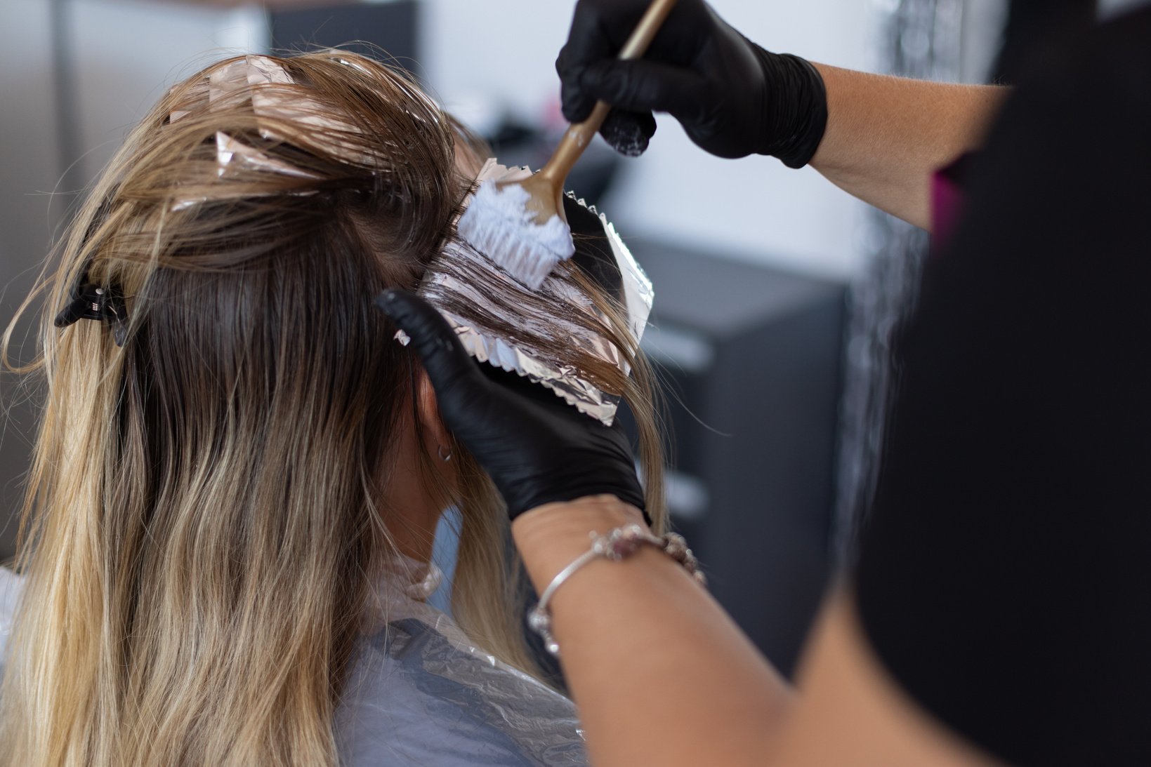 Putting hair dye on the strand of hair. Colouring hair.